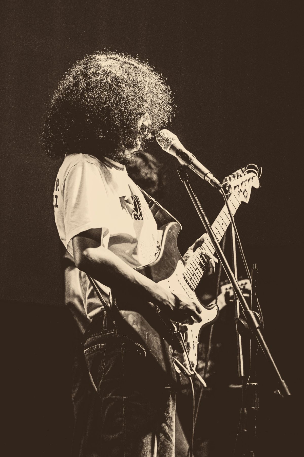 A guitarist on stage, warmly lit, mid-performance